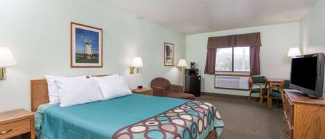 A hotel room with a bed, a desk with a TV, a chair, a window with curtains, and a painting on the wall.