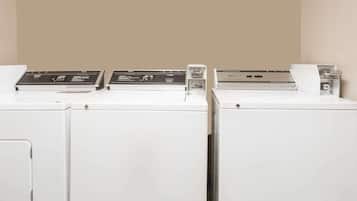 A row of white washing machines with control panels, set against a plain wall.