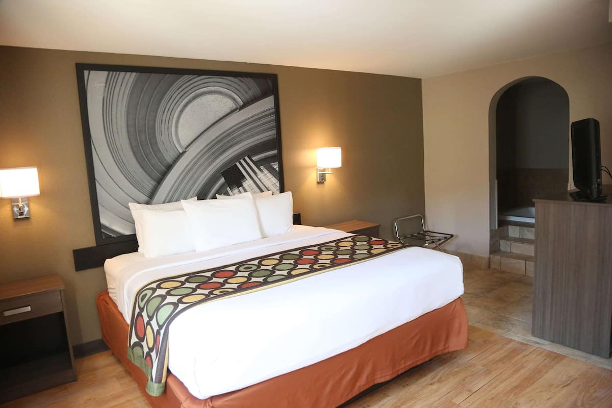 Una habitación de hotel con una cama grande, dos lámparas de noche, un televisor y un cuadro en la pared.