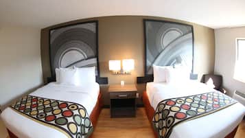 A hotel room with two beds, a nightstand, two wall-mounted lamps, and a large abstract painting on the wall.