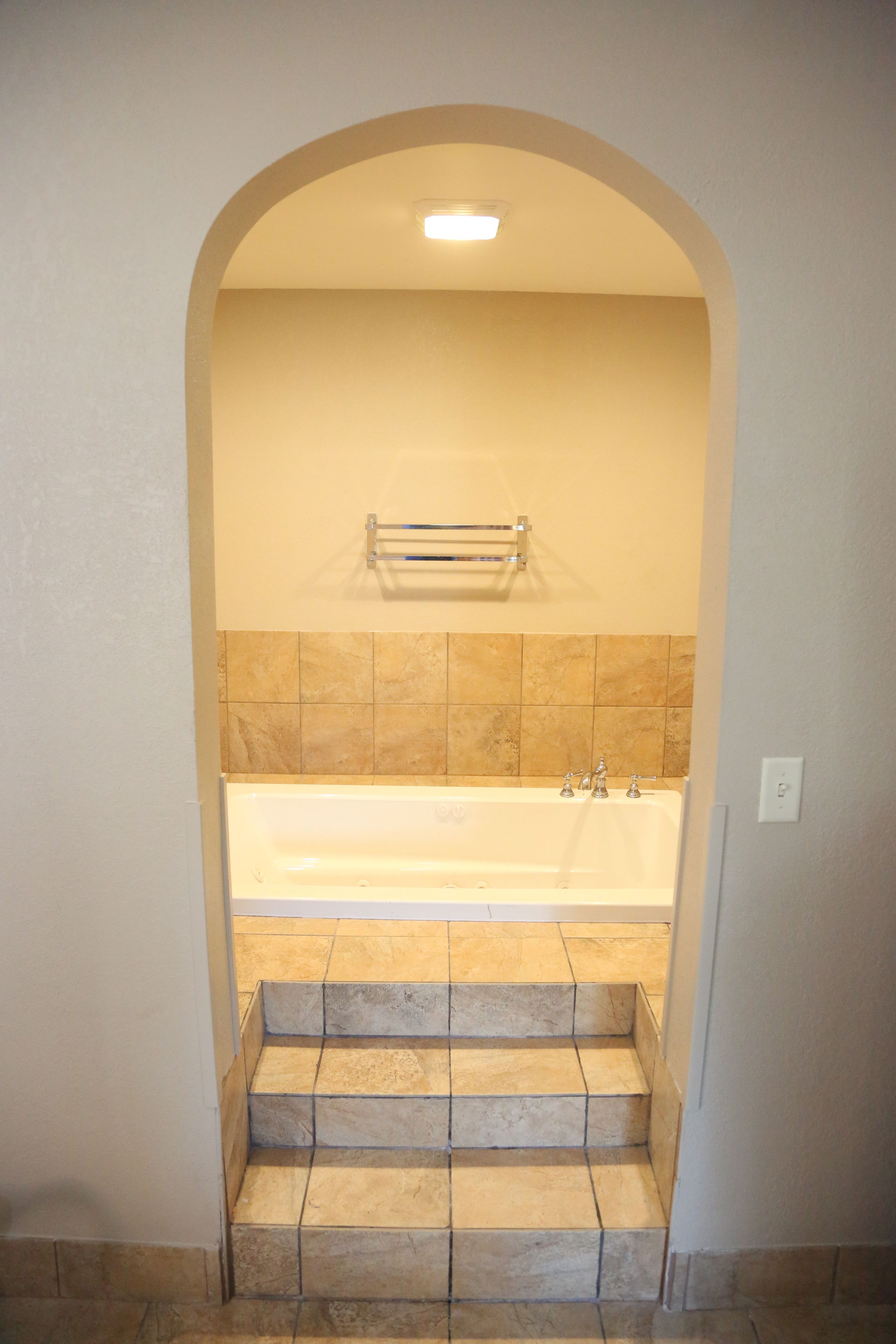 Un baño con bañera, toallero y paredes de azulejos.