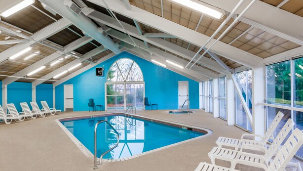 An indoor swimming pool with clear blue water, surrounded by white lounge chairs. - Wingate by Wyndham Canton/Hall of Fame (Canton)
