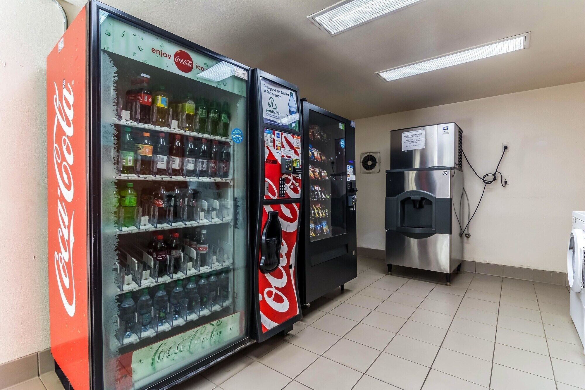 A vending machine area with Coca-Cola and PlantBottle branded machines, a water dispenser, and a coffee machine.