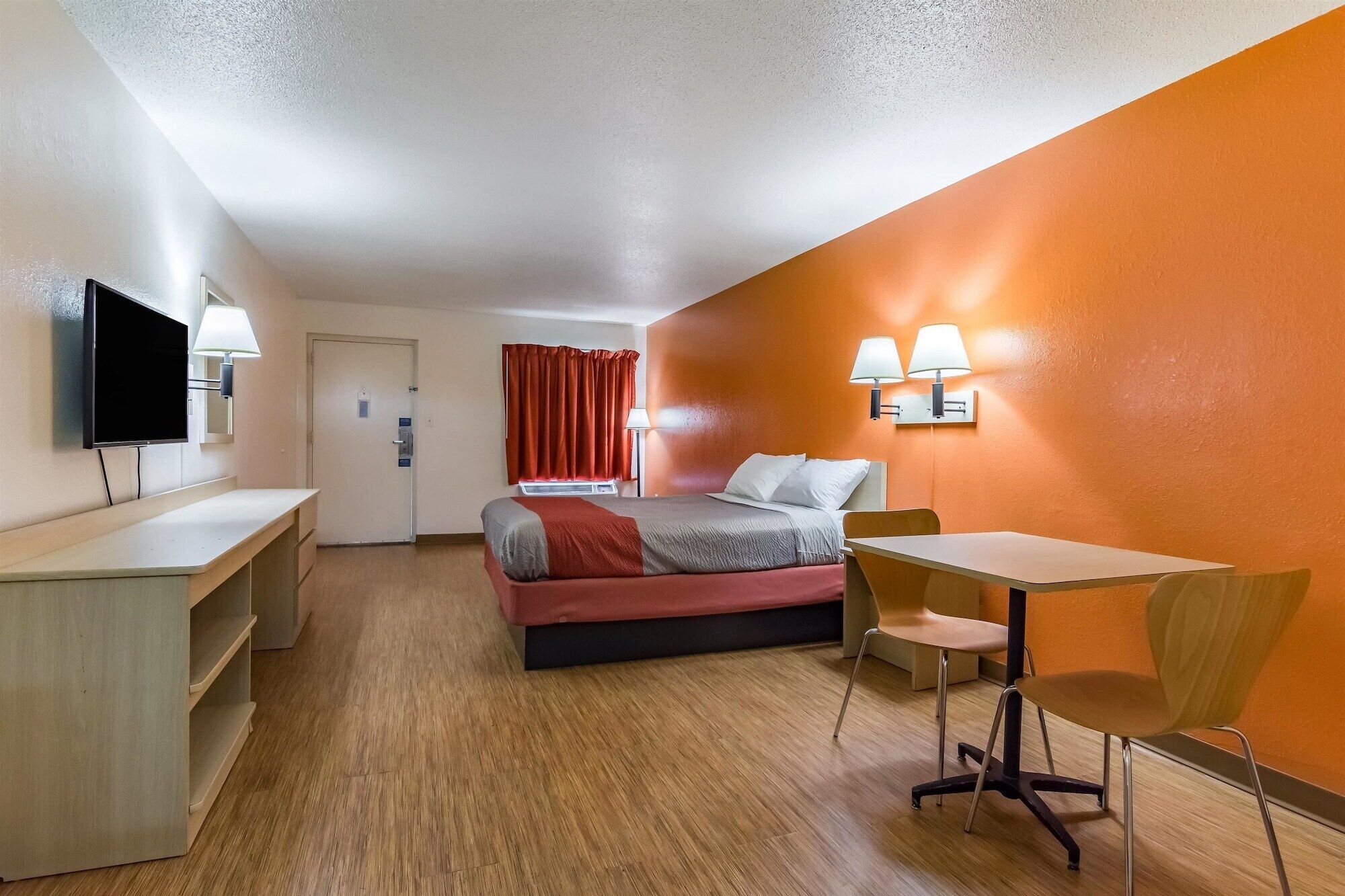 A hotel room with a bed, desk, chair, and TV.