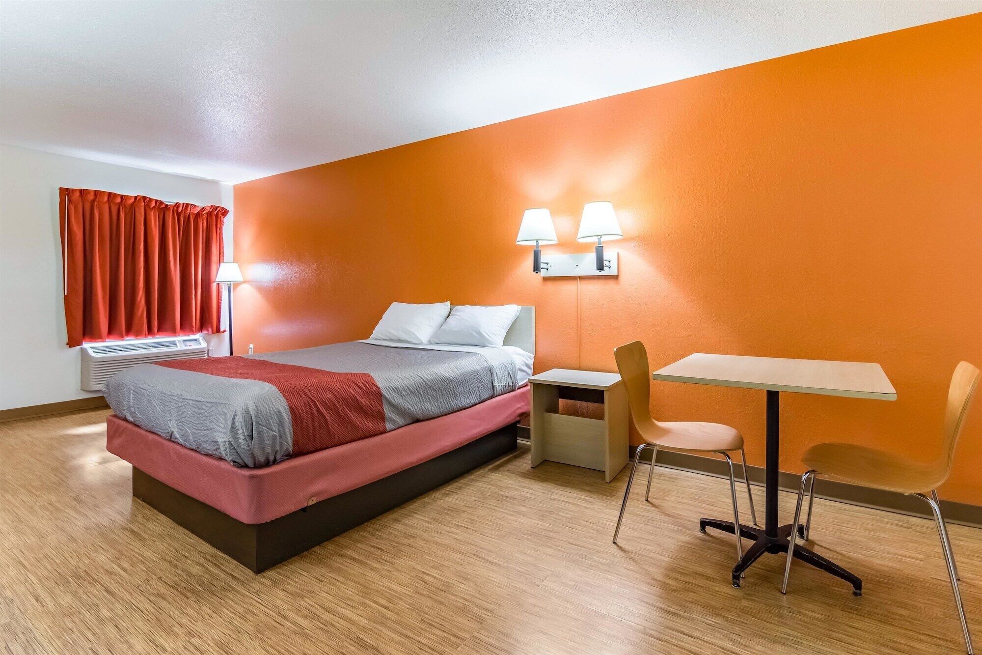 A modern hotel room with a bed, a desk, and a chair.