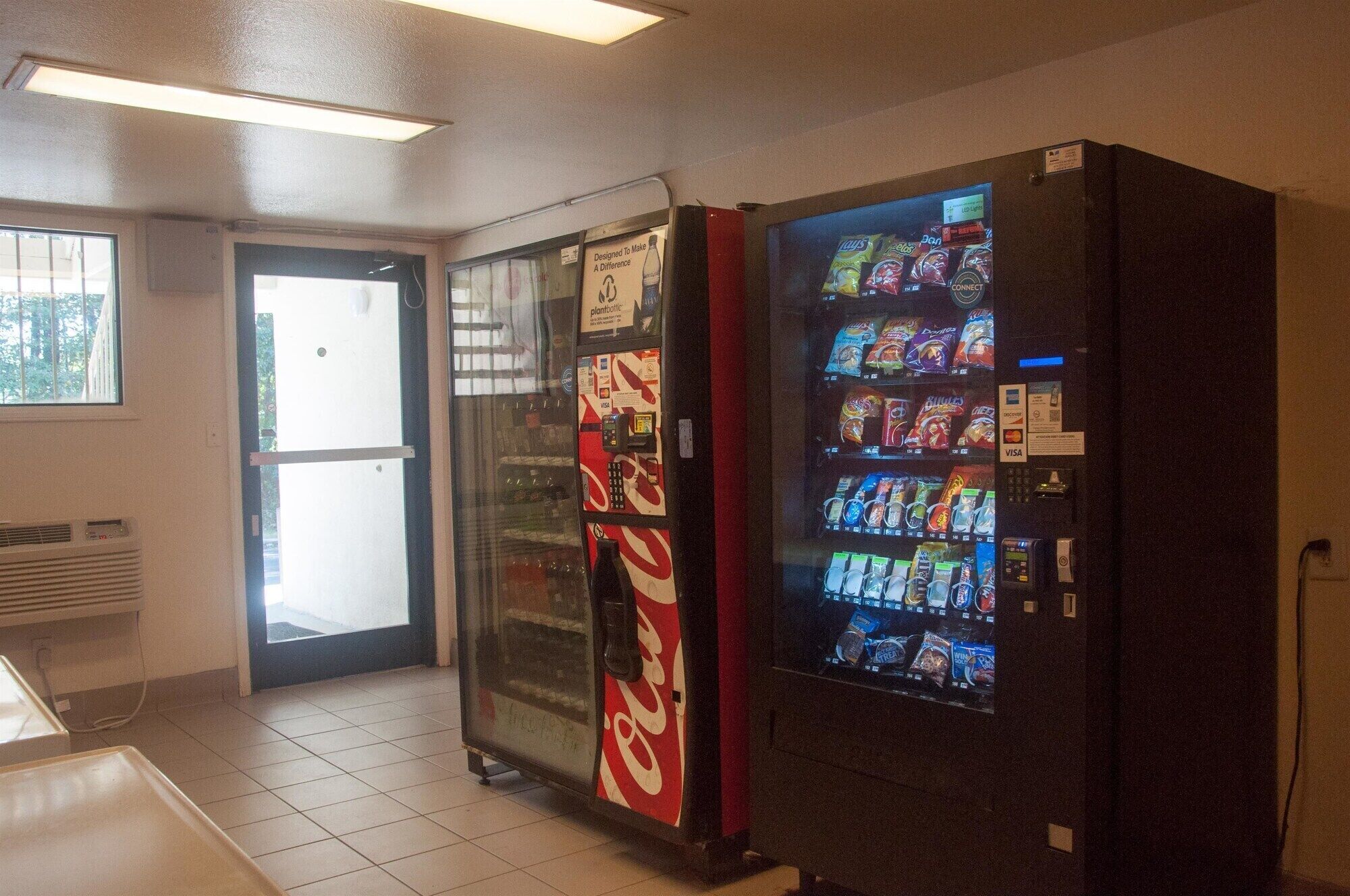 Et automatområde med et Coca-Cola køleskab og forskellige snacks.