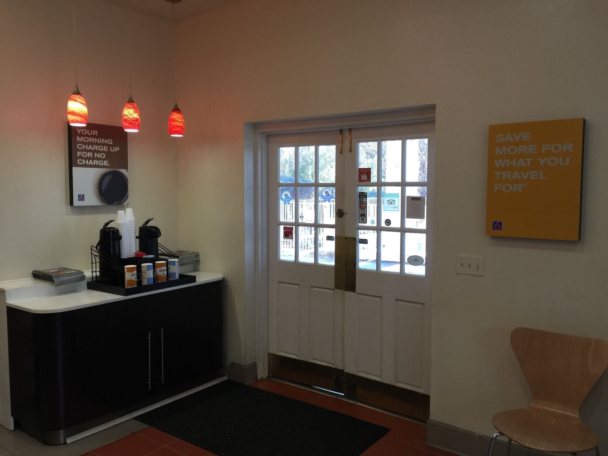 A reception area with a counter, coffee station, and a door leading outside.
