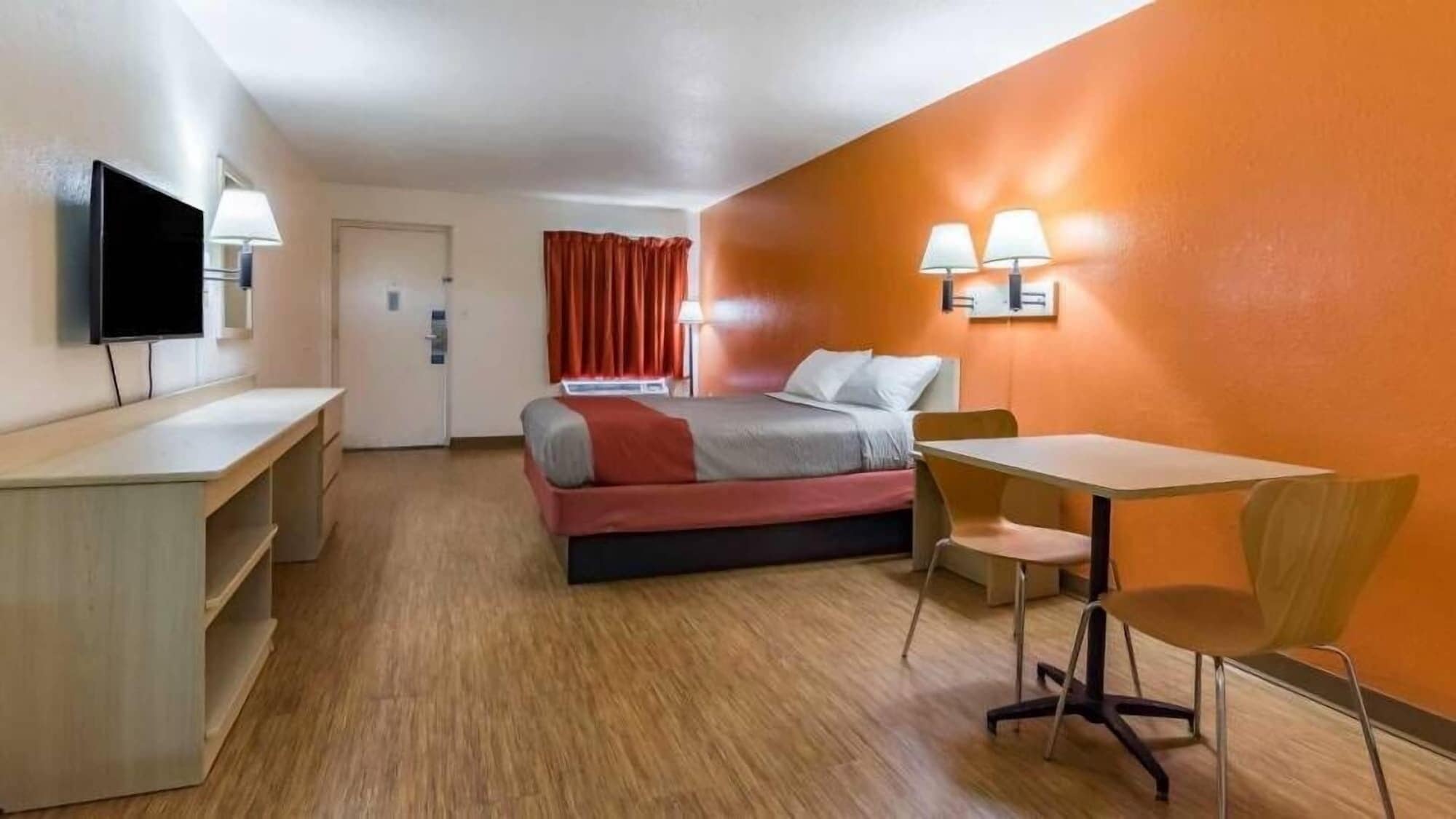 A hotel room with a bed, desk, chair, and TV.