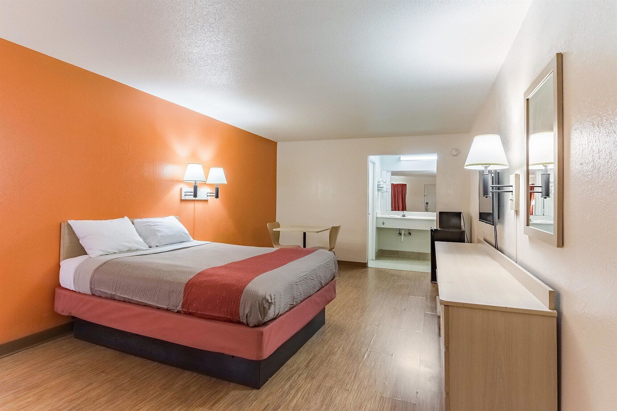 Une chambre d’hôtel avec un lit, une table de chevet et un miroir.