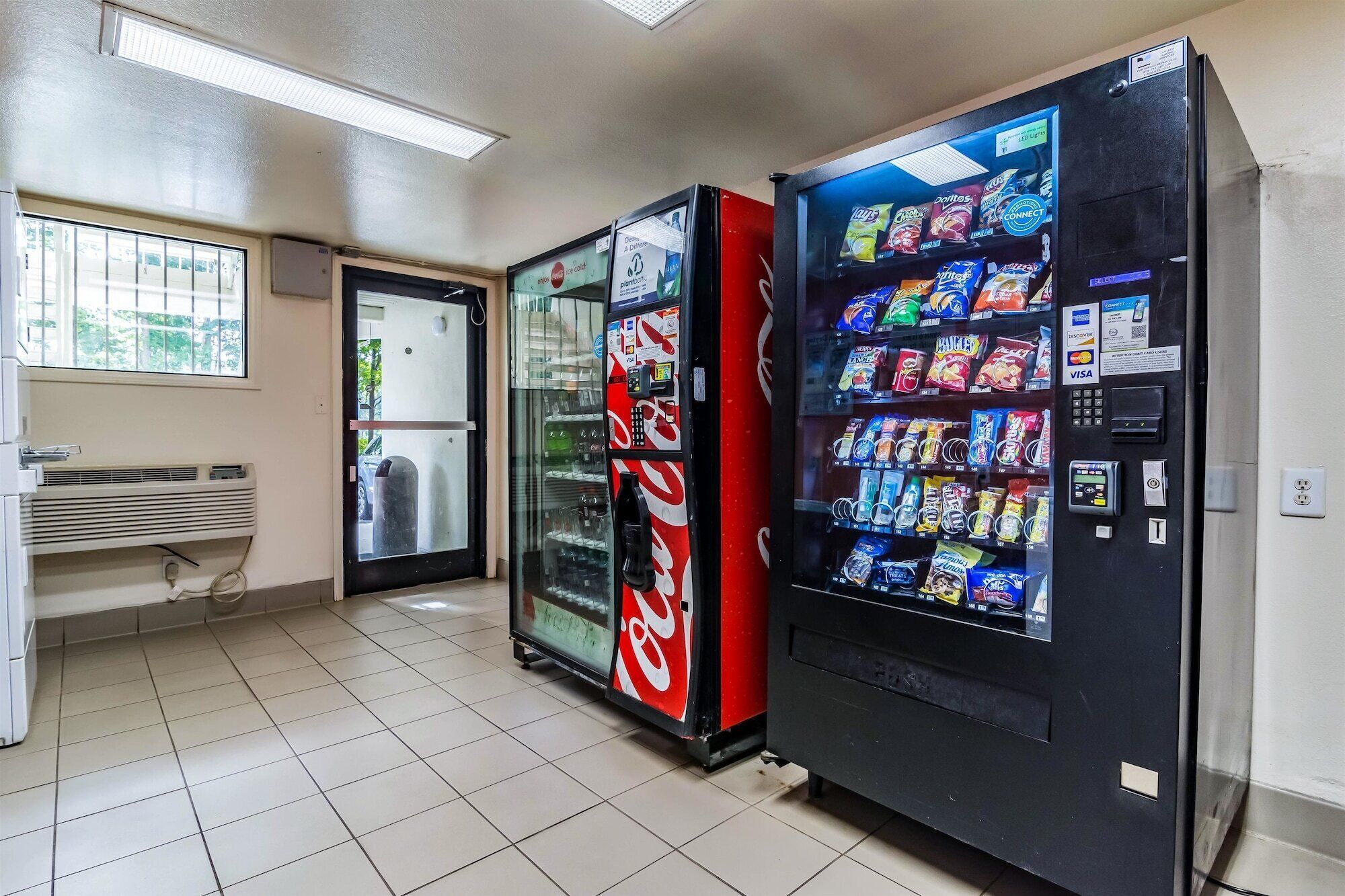 A vending machine area with a Coca-Cola refrigerator and a snack vending machine.