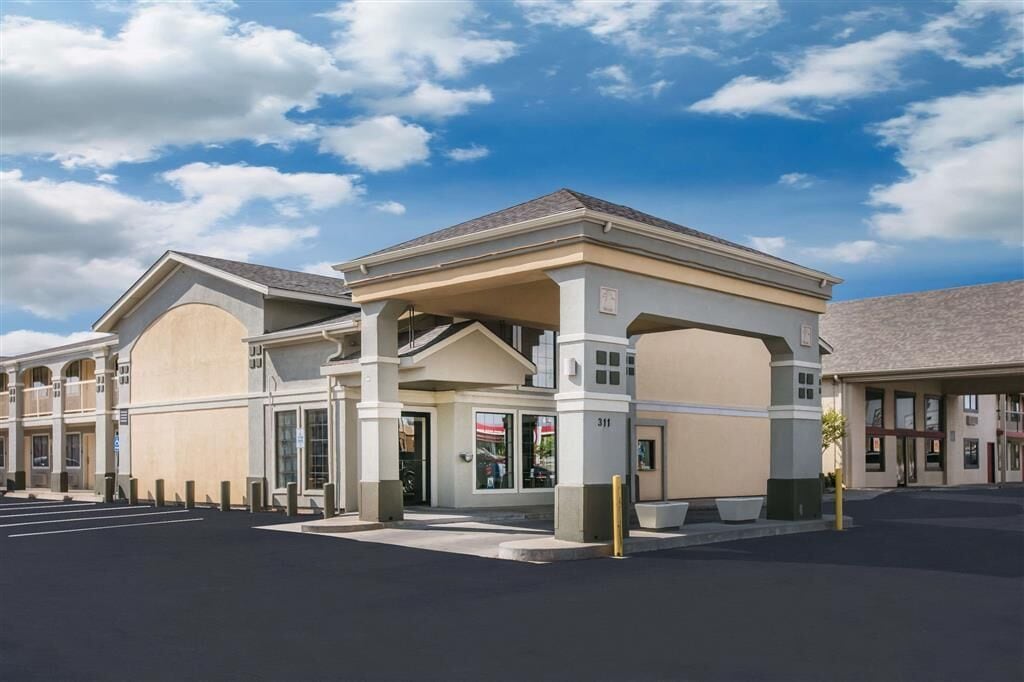 A modern hotel with a covered entrance, multiple floors, and a parking lot.