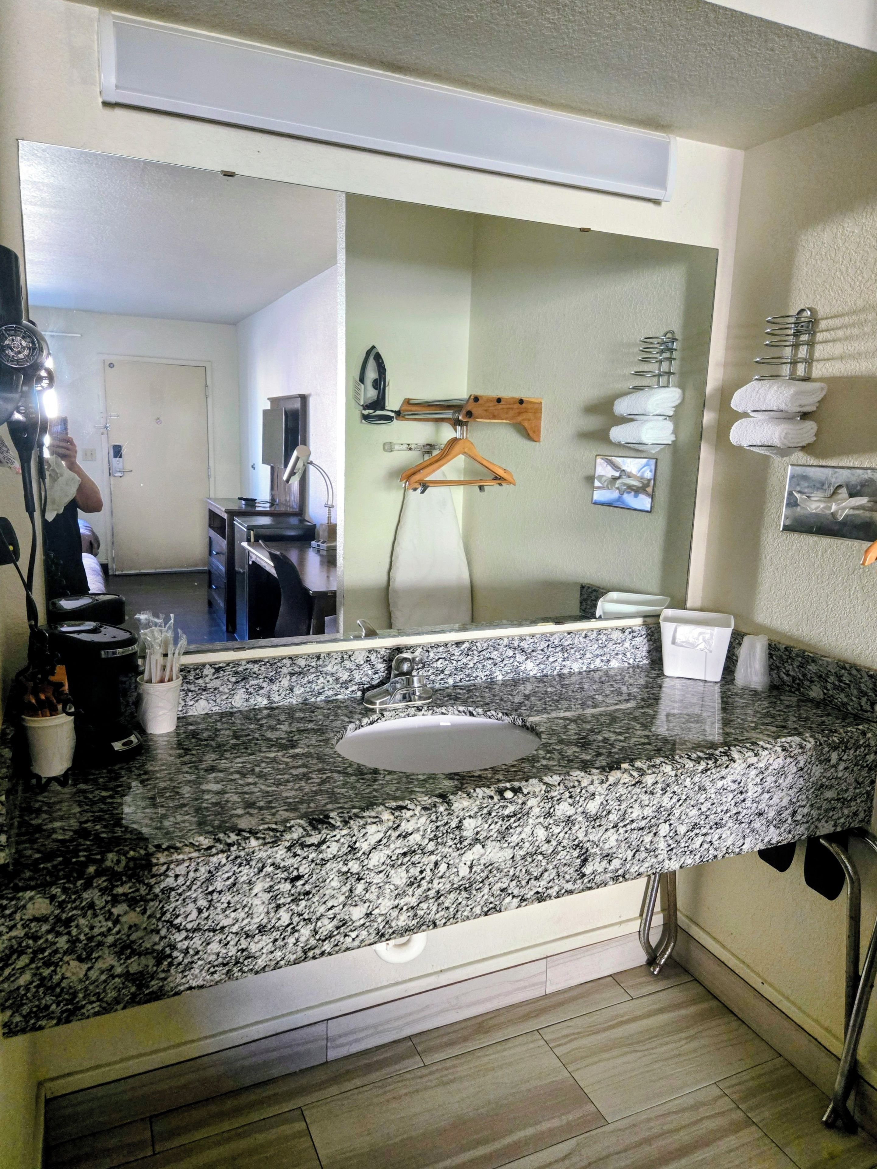 Une salle de bain avec un comptoir en granit, un lavabo, un miroir et un porte-serviettes.
