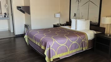 Una habitación de hotel con una cama, una mesita de noche, una lámpara y un cuadro en la pared.