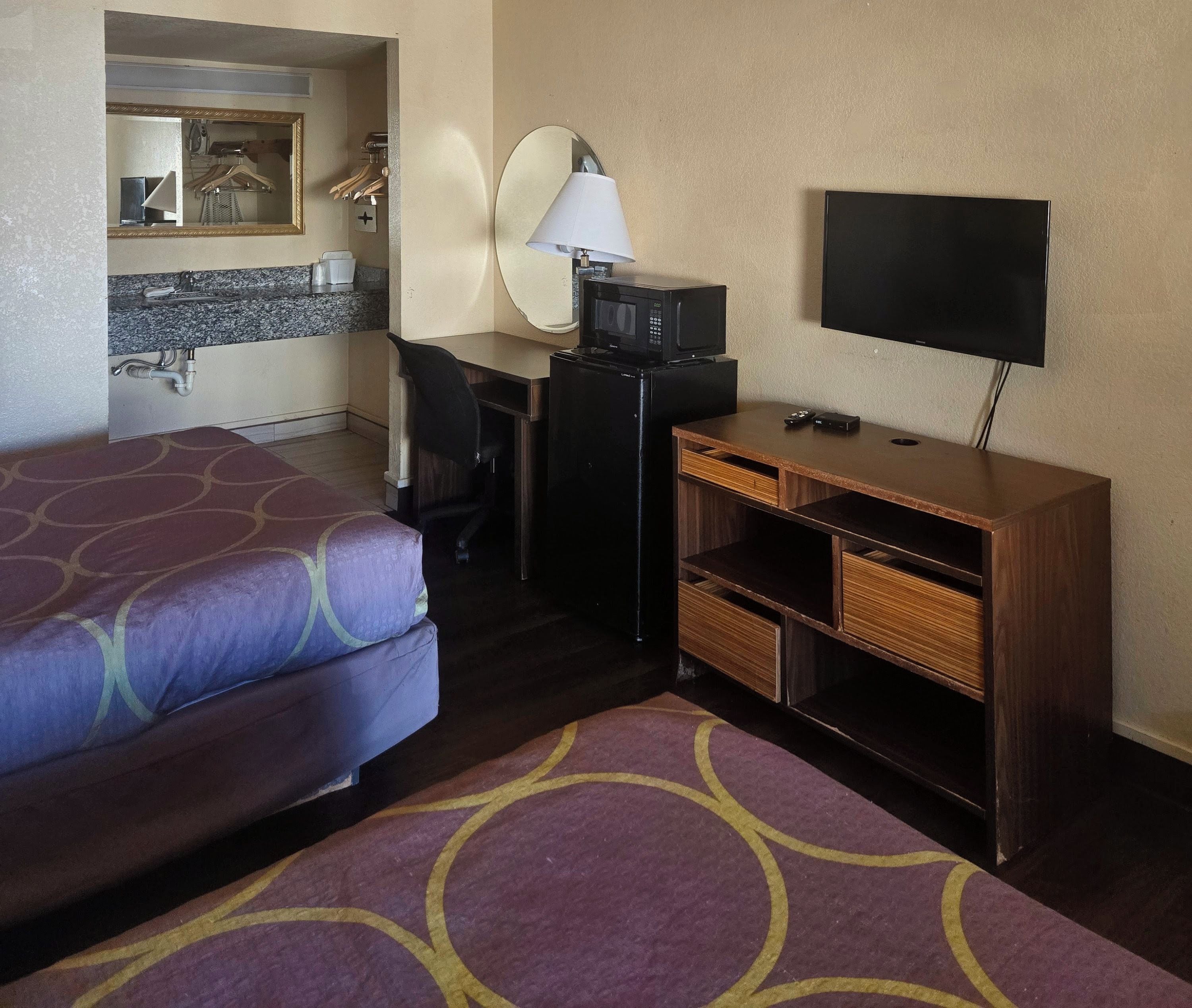 Ein Hotelzimmer mit zwei Betten, einem Schreibtisch mit Fernseher, einer Mikrowelle und einer kleinen Küchenzeile.