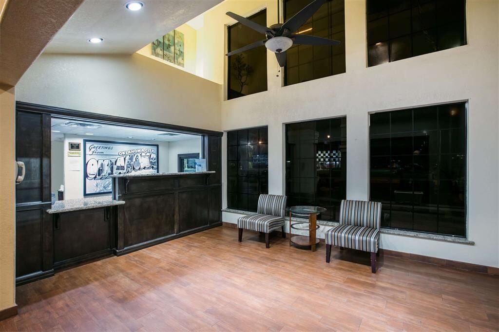 A spacious lobby with a reception desk, two chairs, a ceiling fan, and large windows.