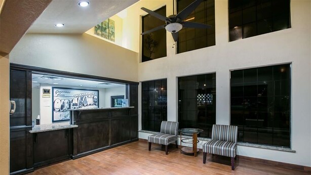 A spacious lobby with a reception desk, two chairs, a ceiling fan, and large windows.