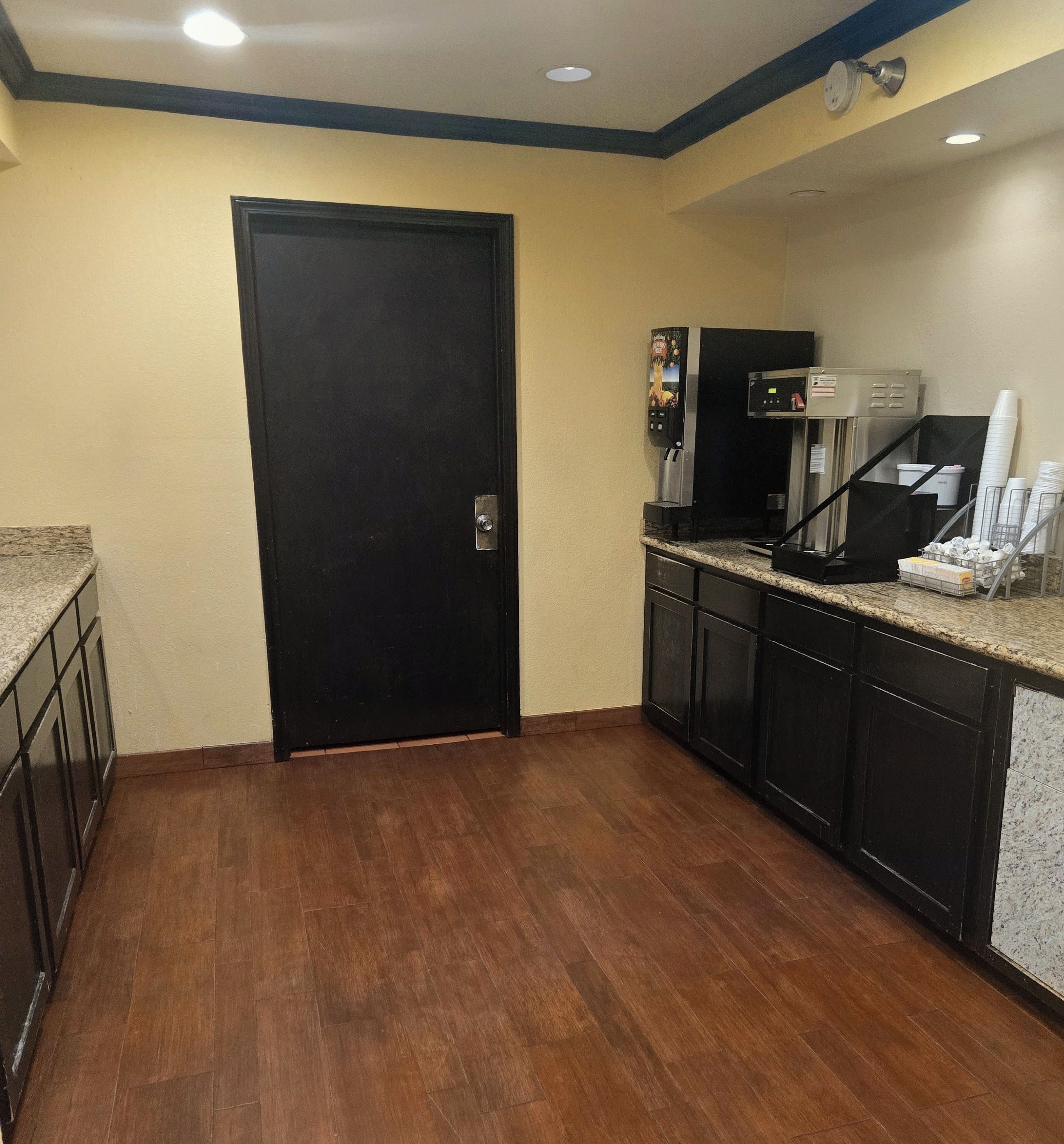A kitchen with a black door, a coffee machine, and a microwave.
