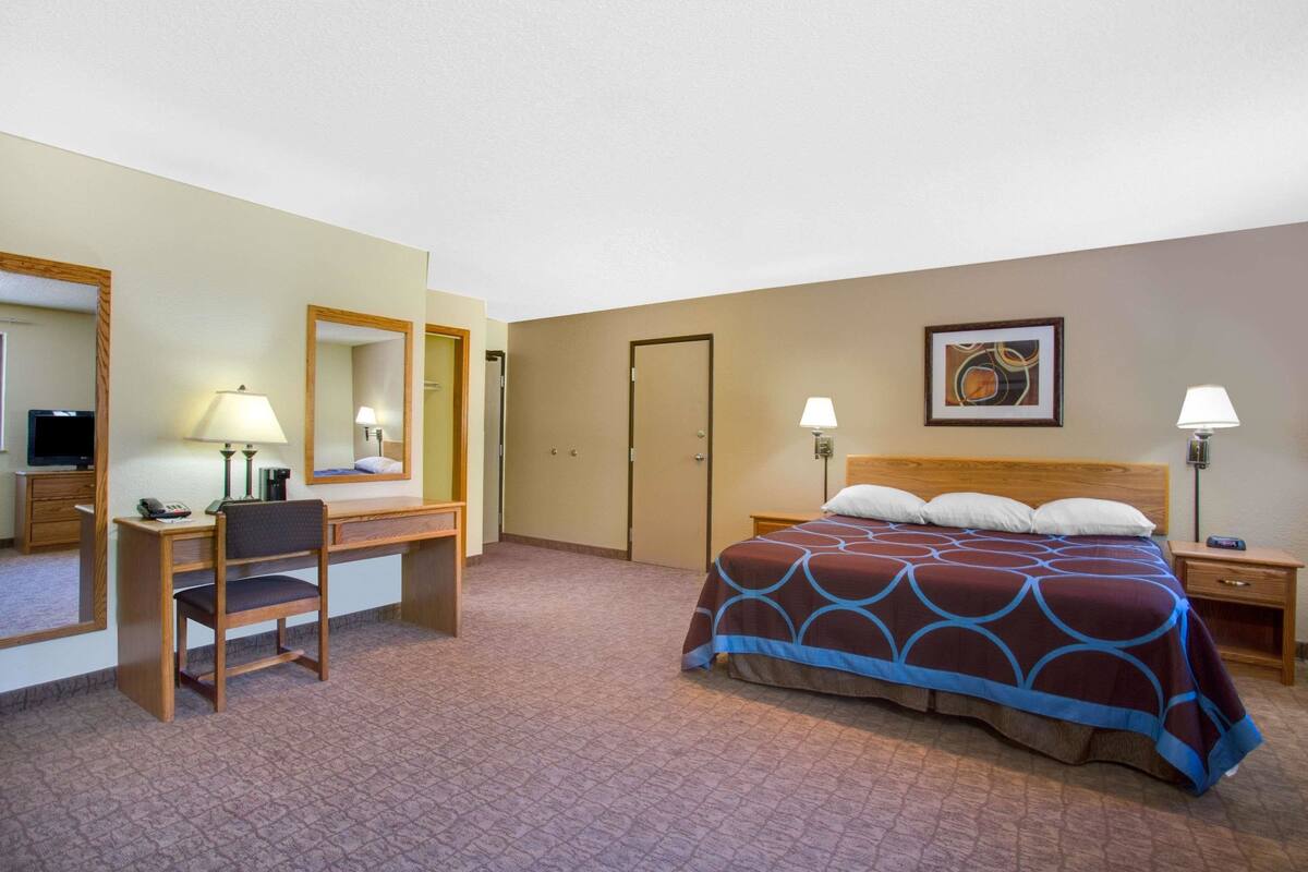 Una habitación de hotel con cama, escritorio, silla, televisor y puerta.