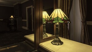 A room with a marble-topped table, a mirror reflecting a stained glass lamp, and a dark carpeted floor. - Inn at Jim Thorpe (Jim Thorpe)