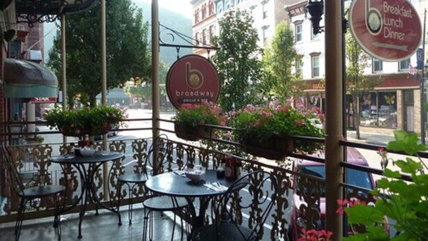 A covered outdoor seating area with tables and chairs, surrounded by buildings and a sign for 'broadway'. - Inn at Jim Thorpe (Jim Thorpe)