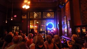A crowded bar with a stage and a neon sign. - Inn at Jim Thorpe (Jim Thorpe)