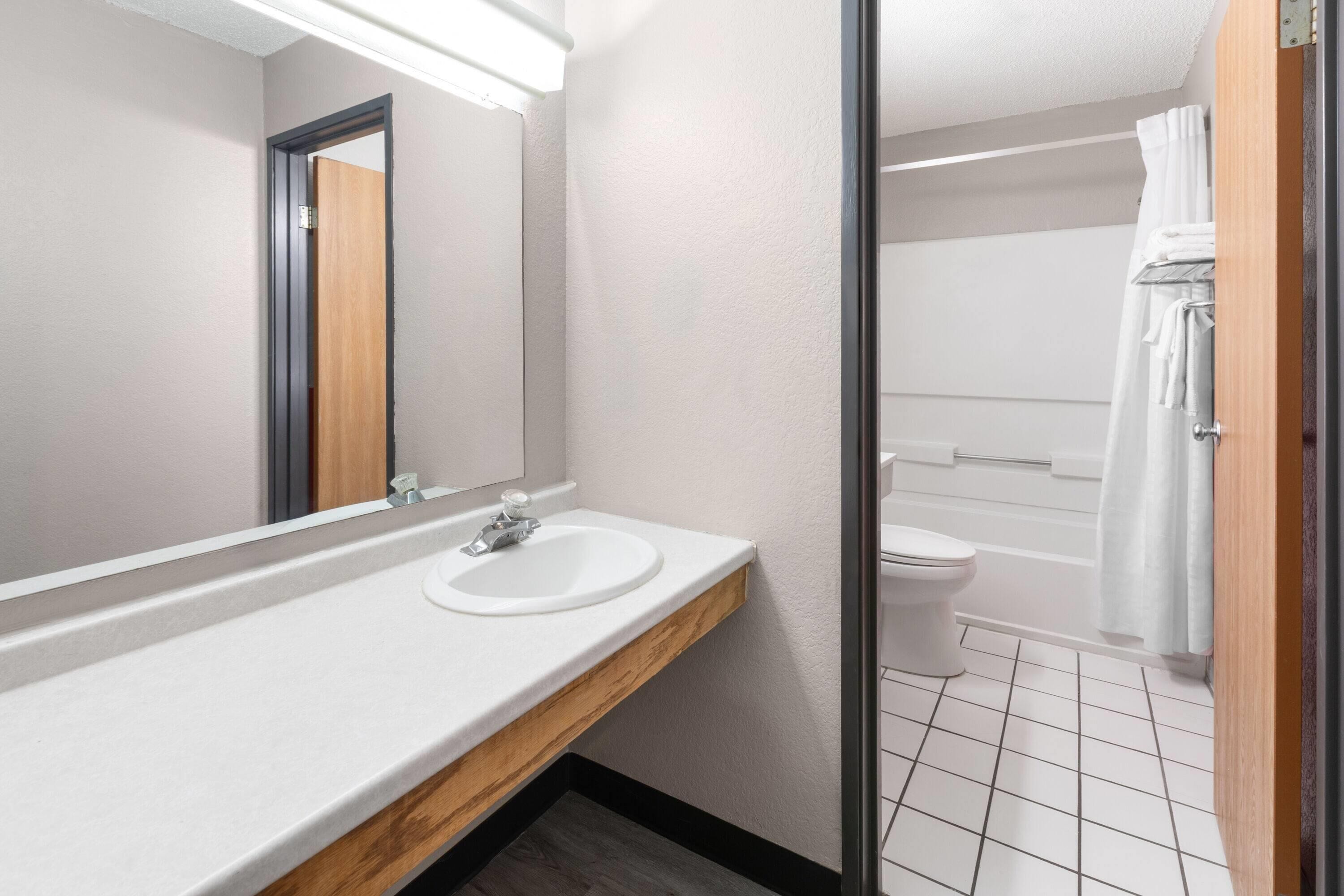 A bathroom with a white sink, mirror, and toilet.