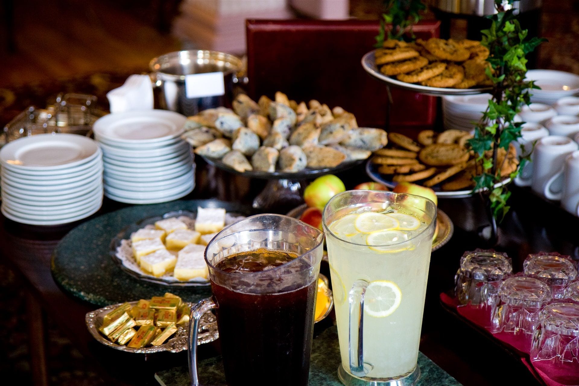 Un tavolo per buffet con diversi cibi, piatti e bicchieri di bevande.
