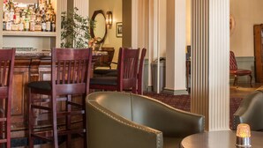 A bar area with wooden chairs, a round table, and a bar stocked with bottles.