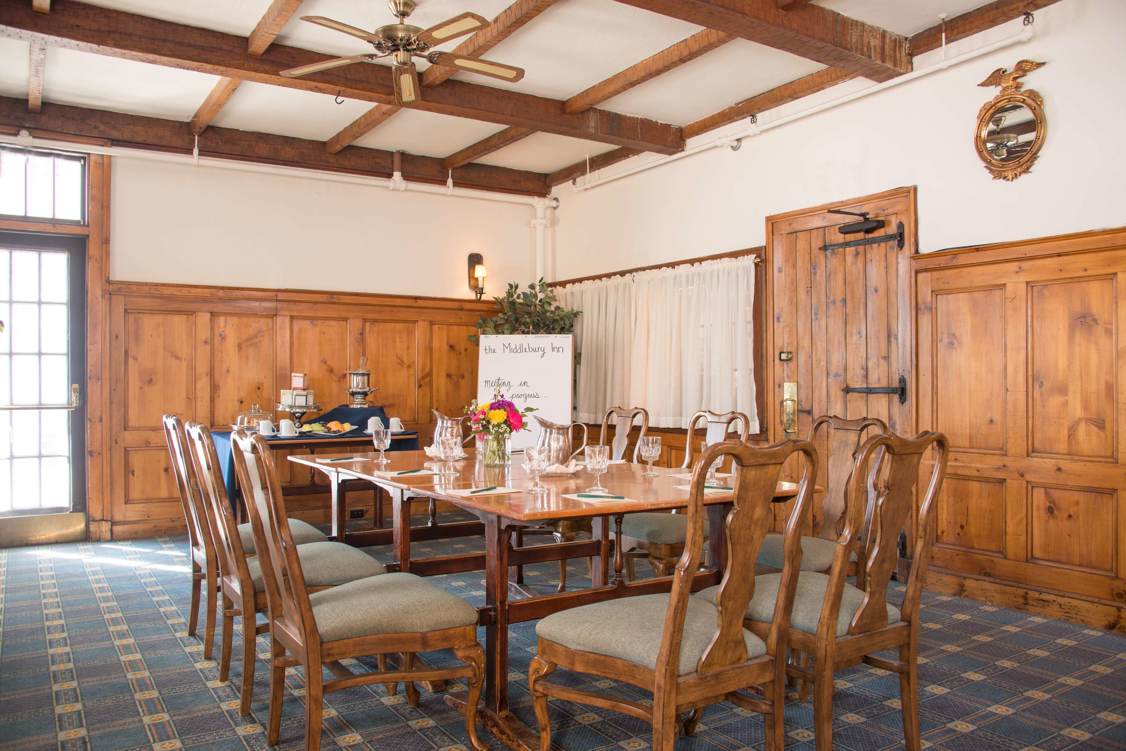 A dining room with a wooden table and chairs, a ceiling fan, and a sign reading "The Middlebury Inn."