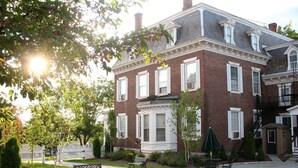 A large brick building with multiple windows and a covered patio area with outdoor seating.