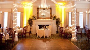 A formal dining room with a fireplace, chandeliers, and string lights.