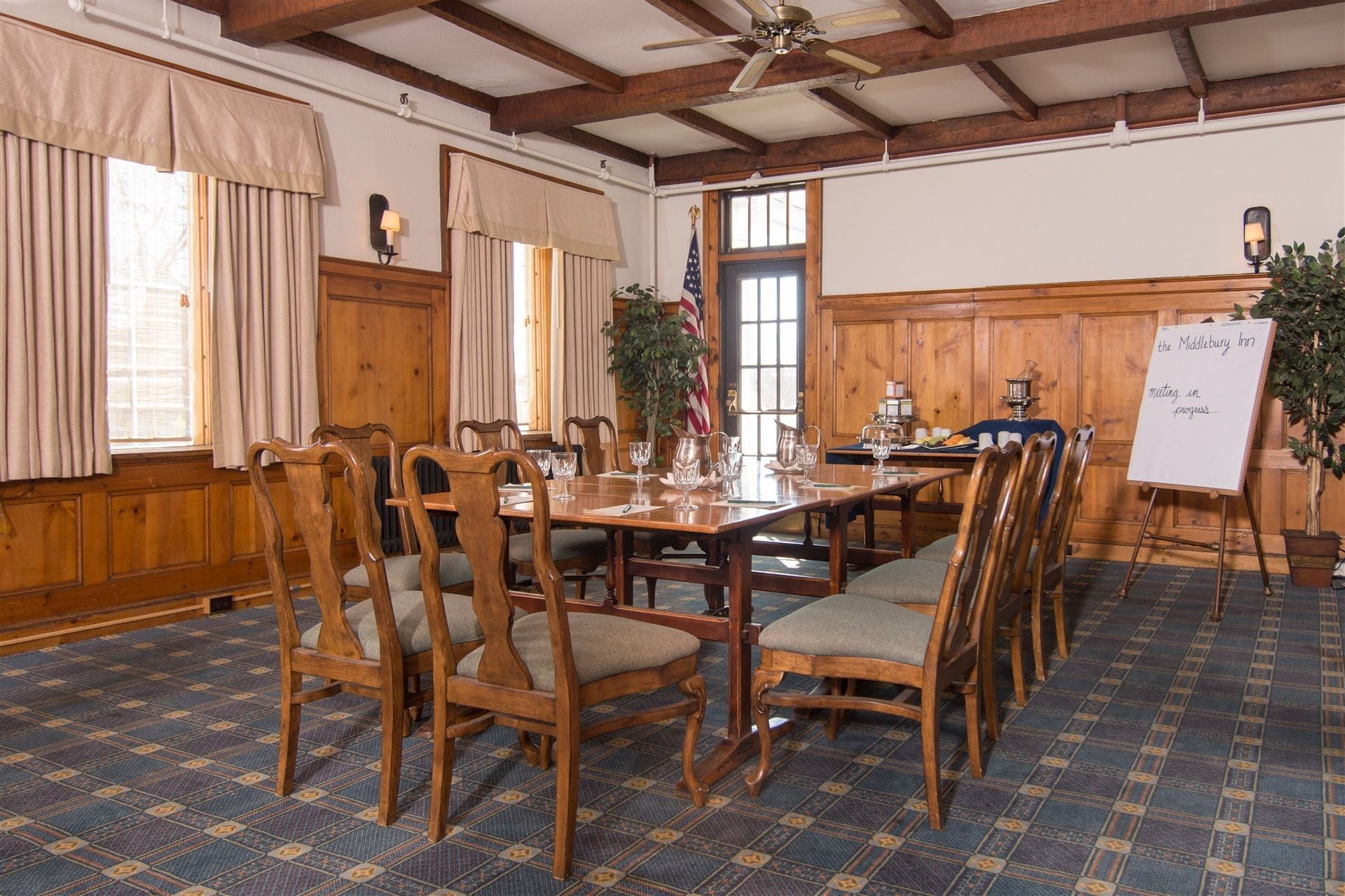 A conference room with a long table, wooden chairs, and a whiteboard.