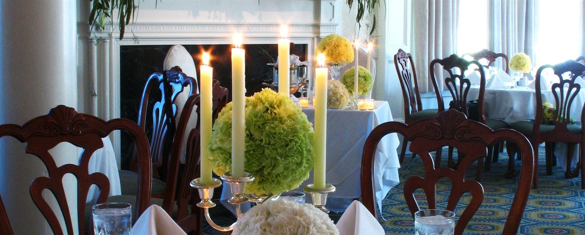 En matplats med en öppen spis, ljus och blomsterarrangemang på borden.