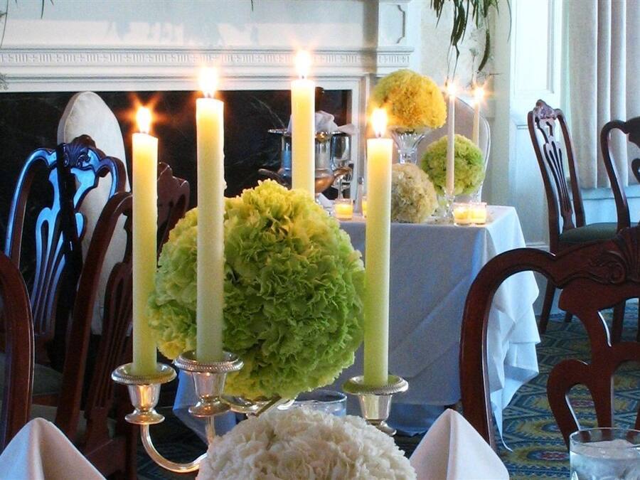 Un comedor con chimenea, velas y arreglos florales sobre las mesas.