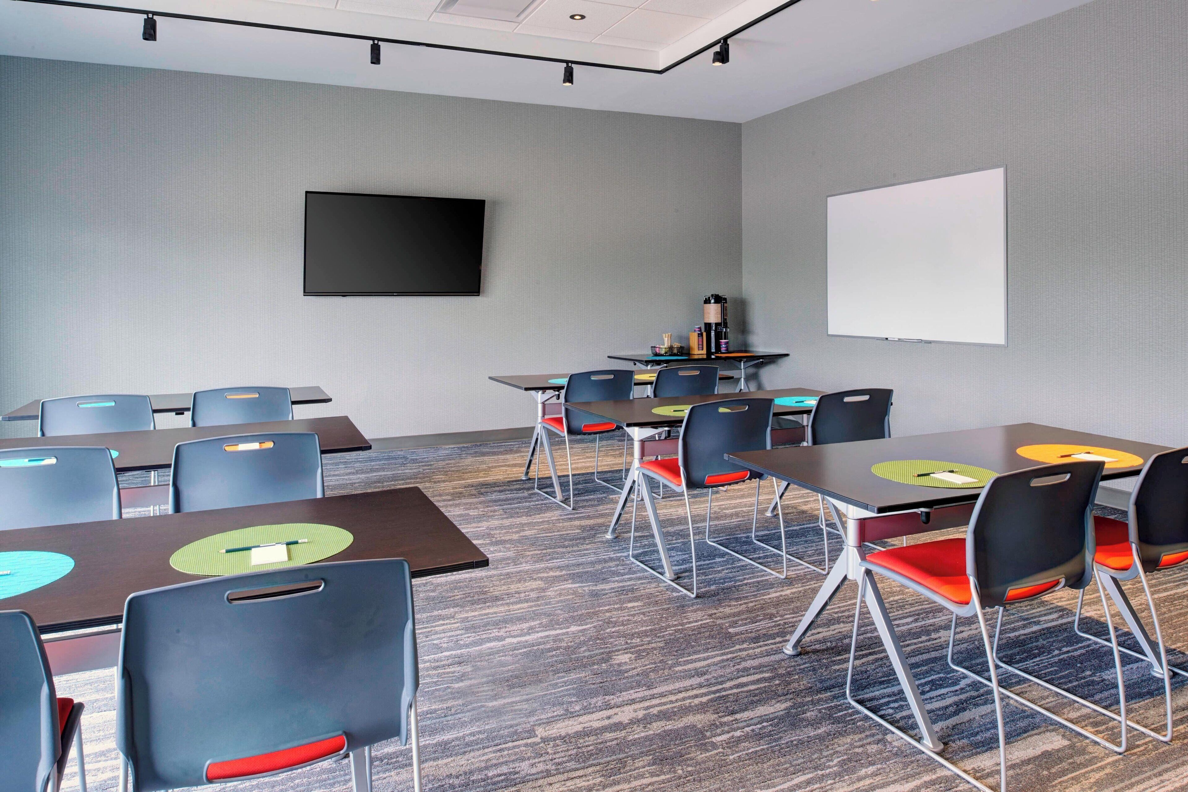 A conference room with tables, chairs, a projector screen, and a whiteboard.