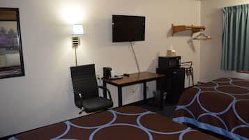 A hotel room with a bed, a desk with a chair, a television, and a lamp.