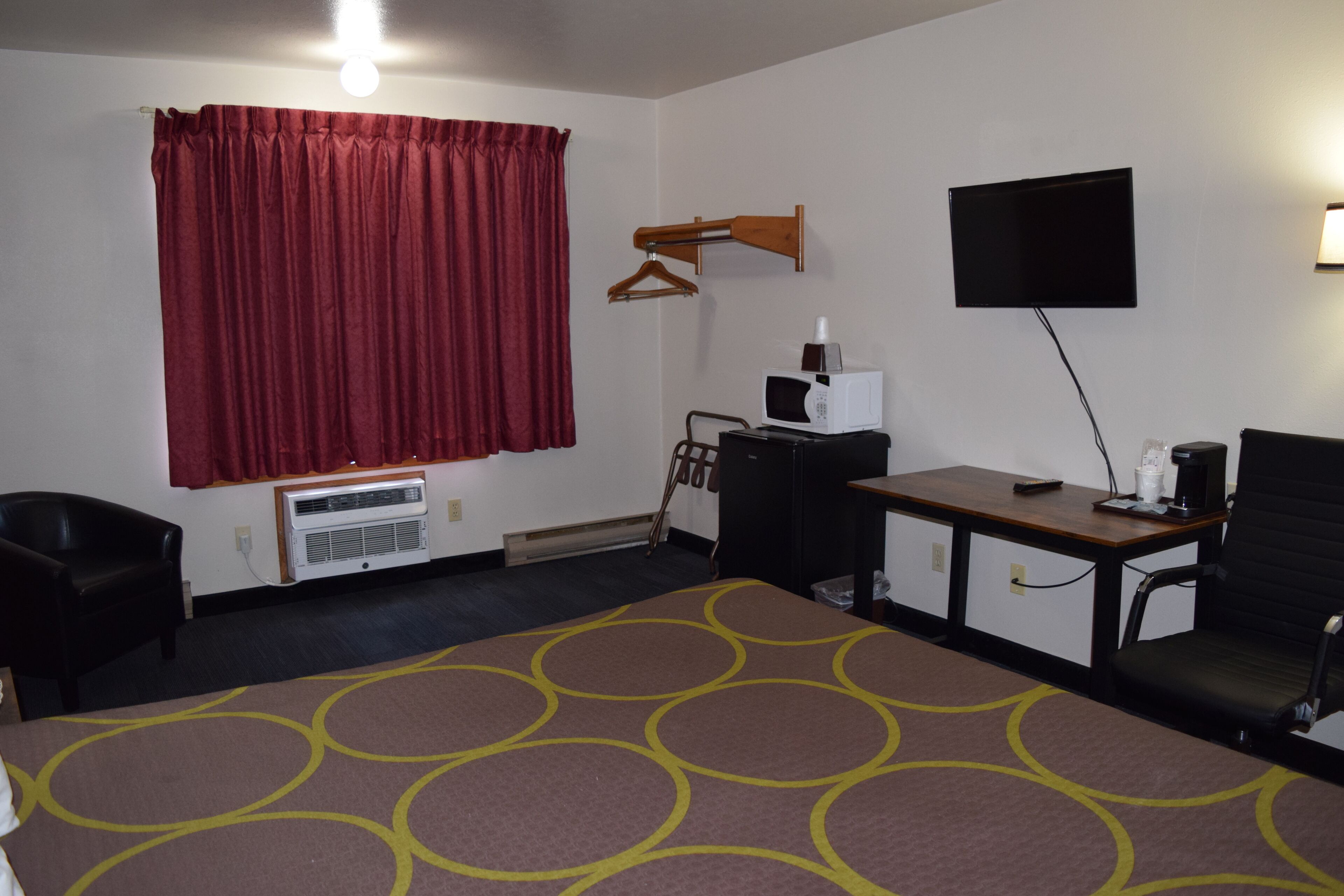Une chambre d’hôtel équipée d’un lit, d’un bureau, d’une chaise, d’une télévision et d’un porte-manteau.