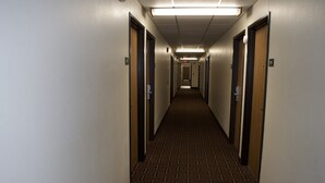 A long, narrow hotel corridor with carpeted floors and doors on both sides.