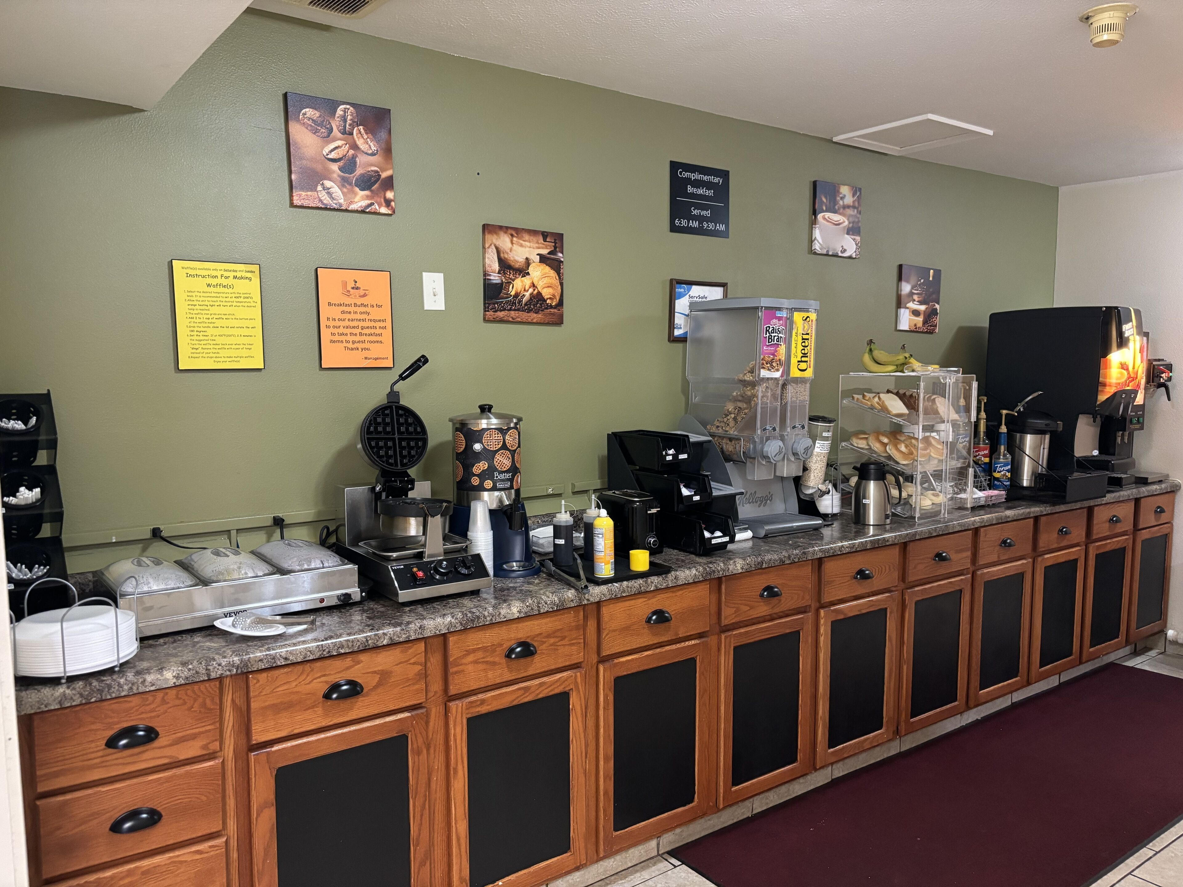 A breakfast bar with waffle makers, coffee machines, and a variety of breakfast items.