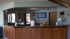 A reception desk with a wooden finish, a clock, and a sign for AmeriVuu Inn & Suites.