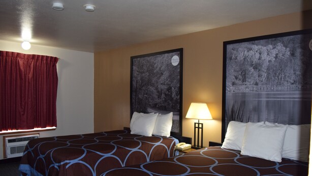 A hotel room with two beds, a red curtain, a wall-mounted air conditioner, and two framed pictures.