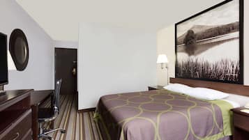 Een hotelkamer met een bed, een bureau, een stoel, een televisie, een lamp en een schilderij van een meer.