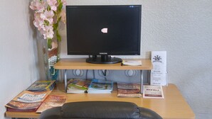 Escritorio de centro de negocios con una computadora, un florero y un letrero que indica el horario de atención.
