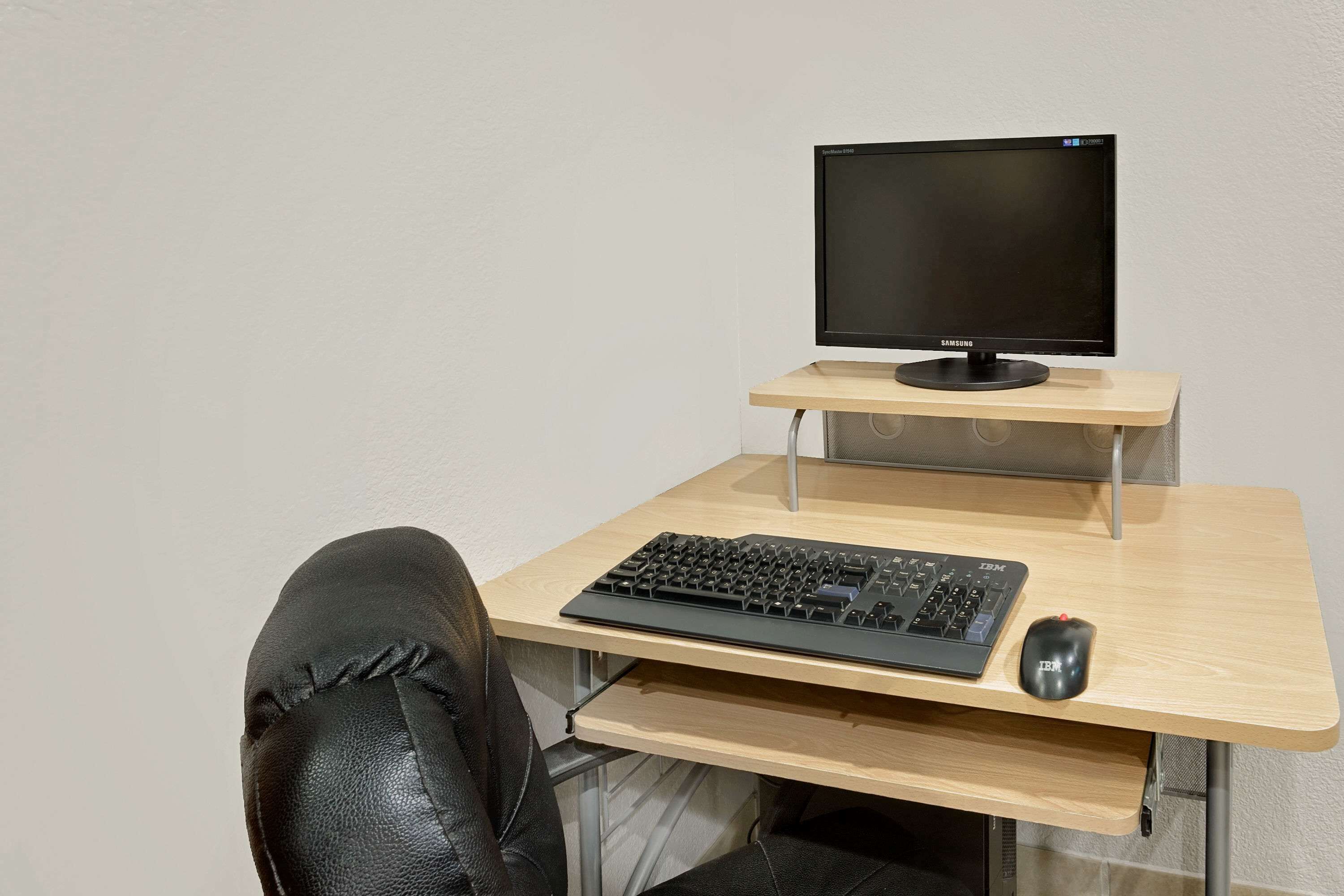 Un espacio de trabajo con monitor, teclado y ratón sobre un escritorio de madera.