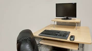 Un espacio de trabajo con monitor, teclado y ratón sobre un escritorio de madera.