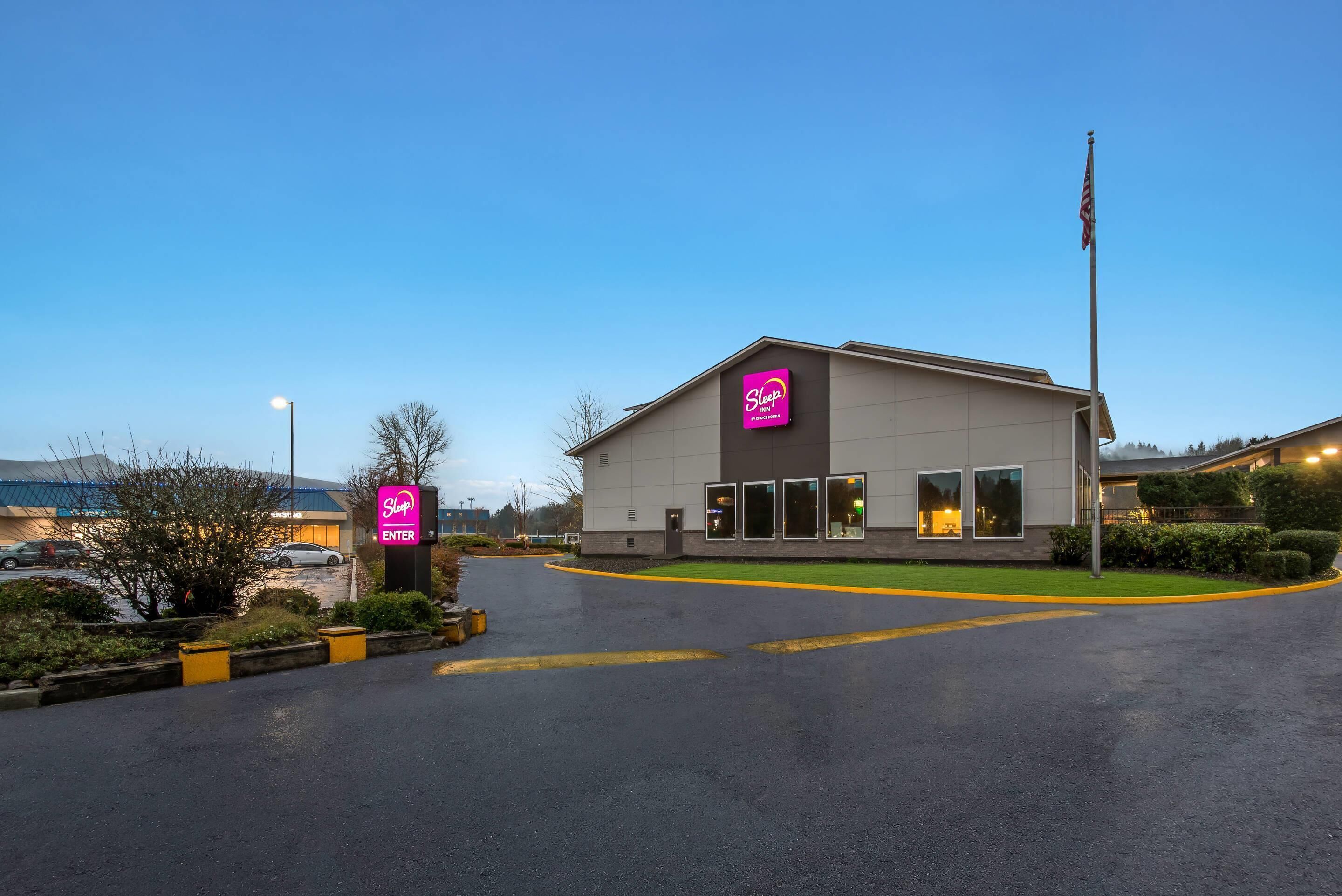 Edifício Sleep Inn da rede Choice Hotels, com estacionamento e mastro de bandeira.