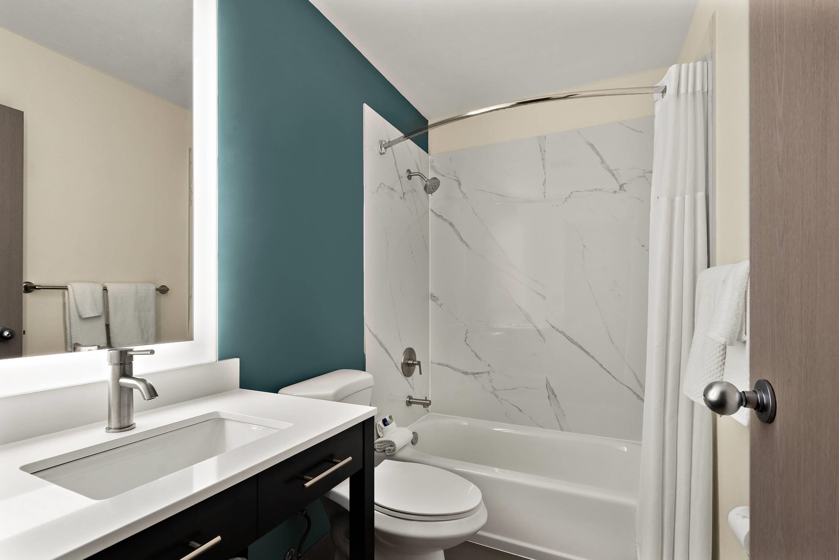 A modern bathroom with a white sink, a toilet, and a bathtub.