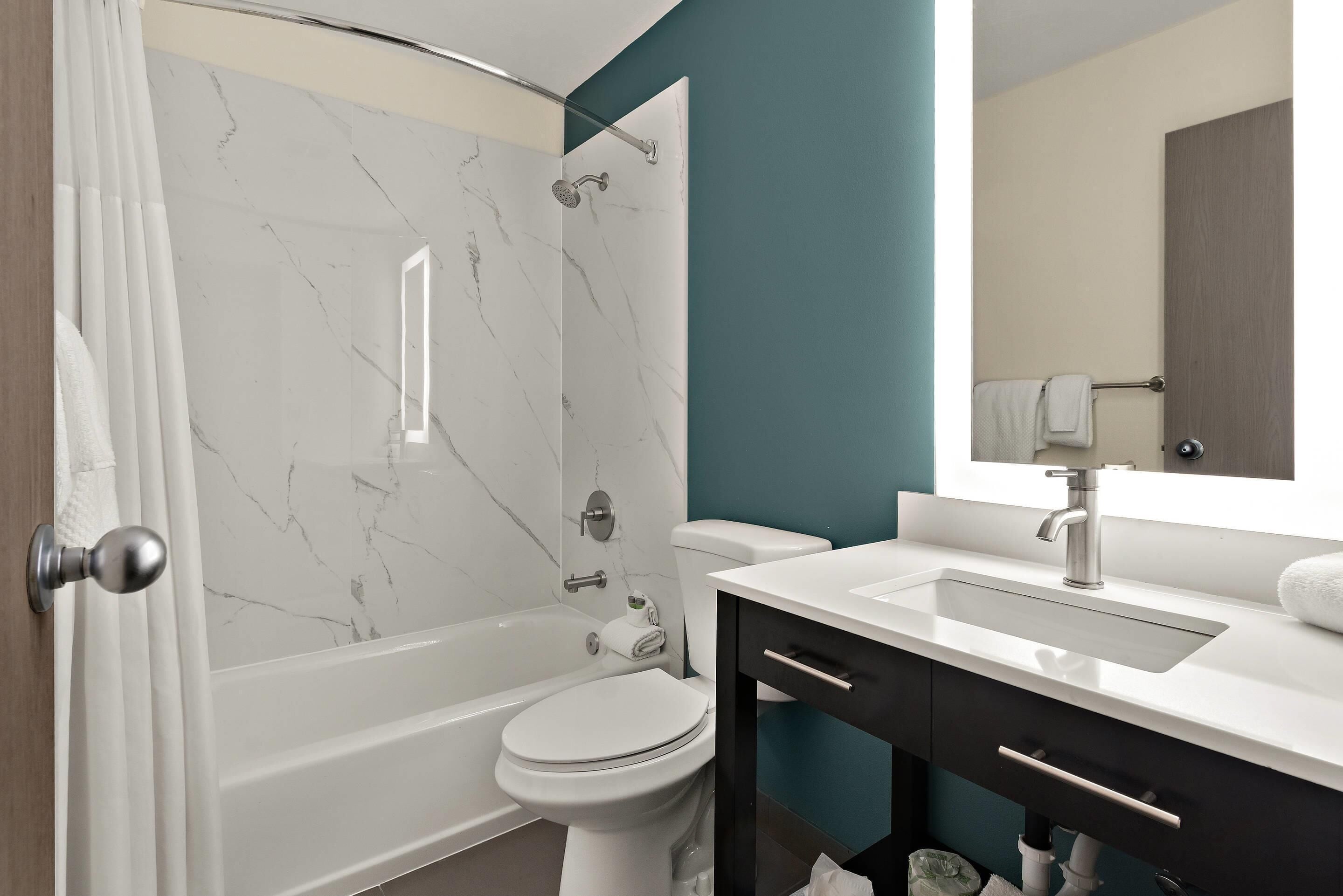 A modern bathroom with a bathtub, toilet, and vanity.