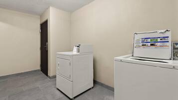 A laundry room with a front-loading washer and dryer, a door, and a wall-mounted instruction manual.