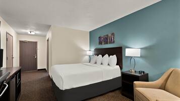 Una habitación de hotel con cama, escritorio, silla y mesita de noche con lámpara.